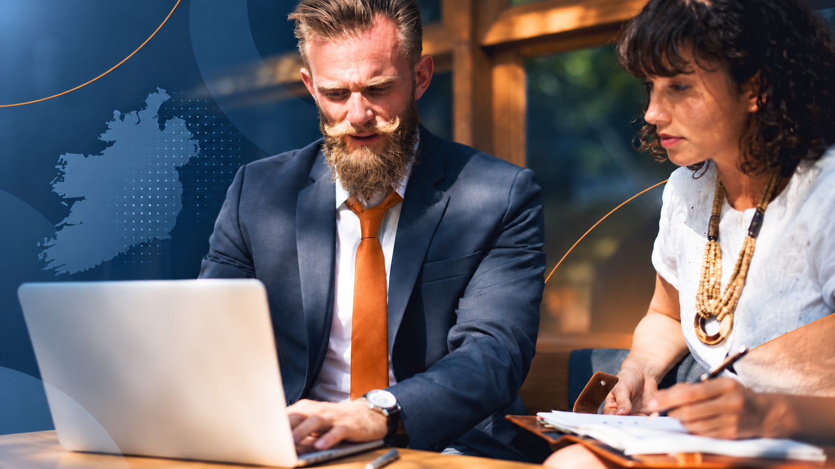 Two business professionals working at a laptop beside a blue map of Ireland