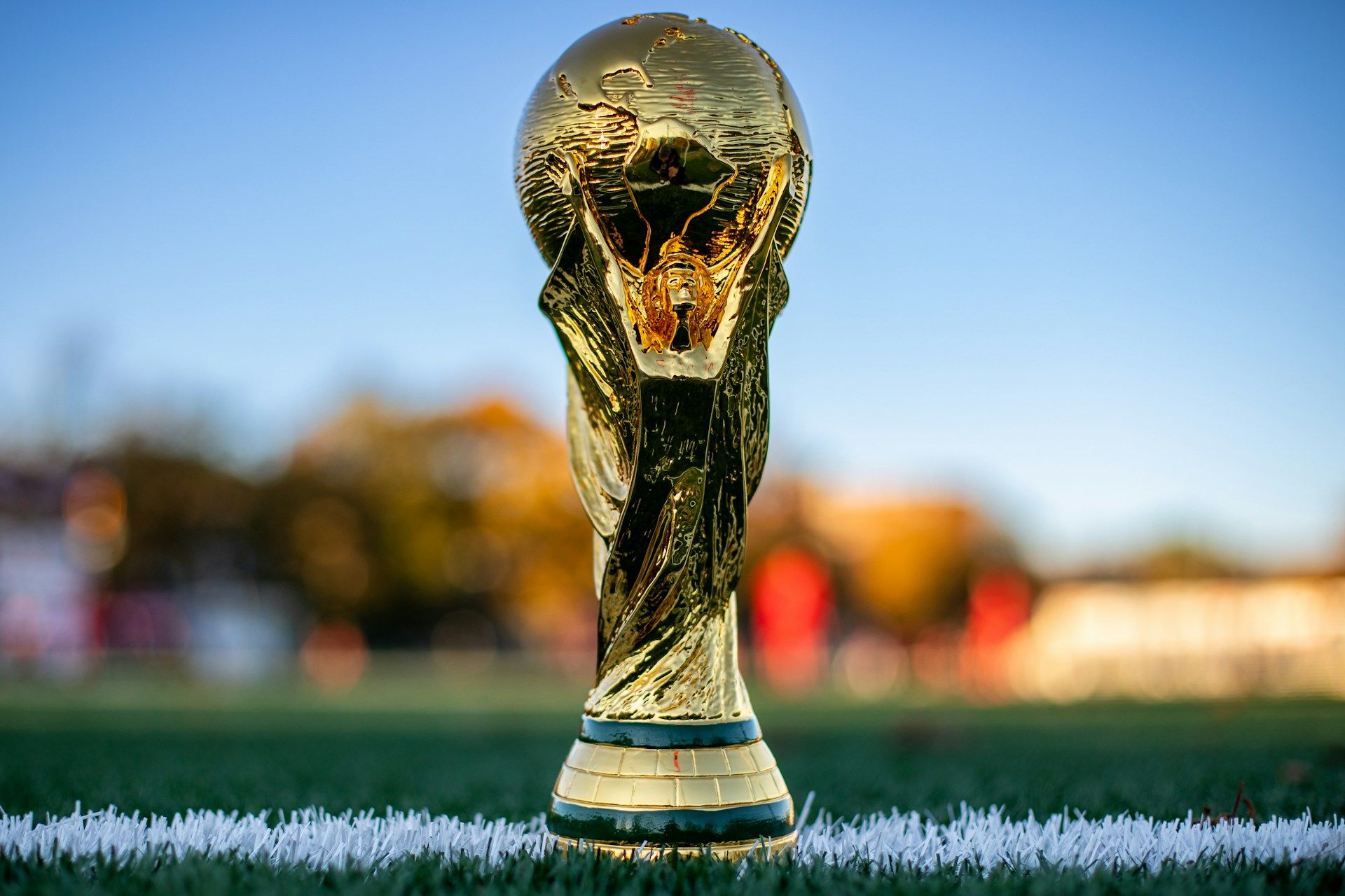 World Cup trophy on a football pitch under stadium lights